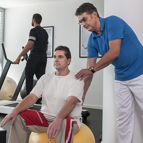 Mann auf Gymnastikball in der Physiotherapie